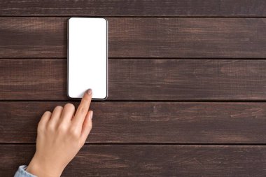 Ahşap arka planda boş ekranlı cep telefonu kullanma