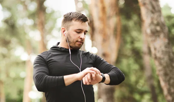 Sportovní muž používající chytré hodinky ke sledování běžícím výkonu. — Stock fotografie