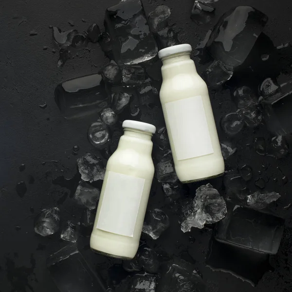 Вегетаріанський кокос або мигдальне молоко в пляшках на чорному — стокове фото