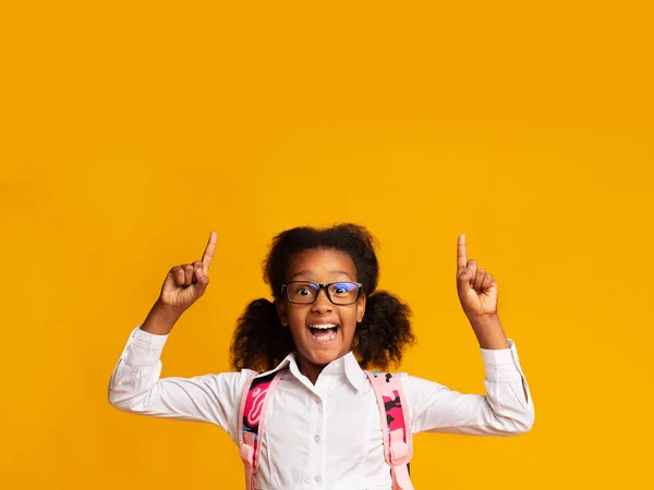 Africano americano escuela chica apuntando dedos hacia arriba, fondo amarillo — Foto de Stock