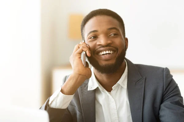 Positive african worker talking on phone with happy face expression
