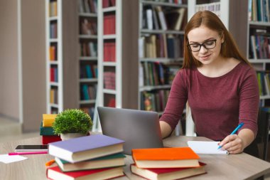 Redhead güzel kız okurken notlar yapma