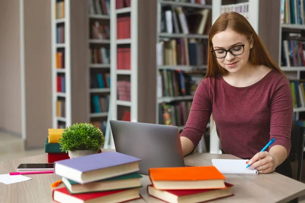 Redhead güzel kız okurken notlar yapma