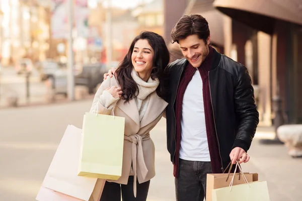 Pareja cariñosa llevando bolsas de compras y caminando en el día de otoño —  Fotos de Stock