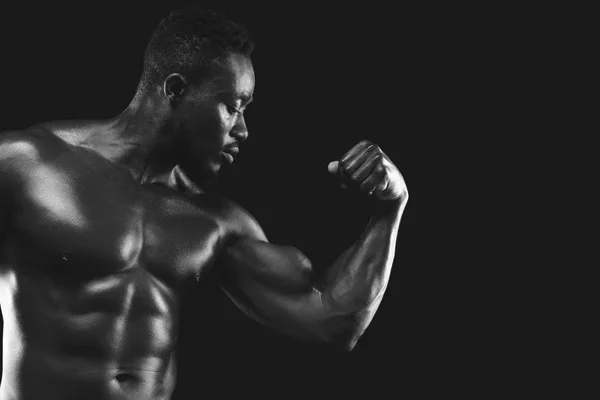 Monochrome photo of african fitness model demonstrating his strong arm — Stock Photo, Image