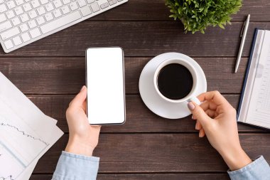 Boş ekranlı akıllı telefonu kullanan ve kahve içen kadın