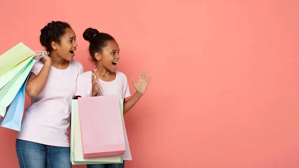 Aufgeregte afrikanische Mädchen mit Einkaufstüten, die zur Seite schauen — Stockfoto