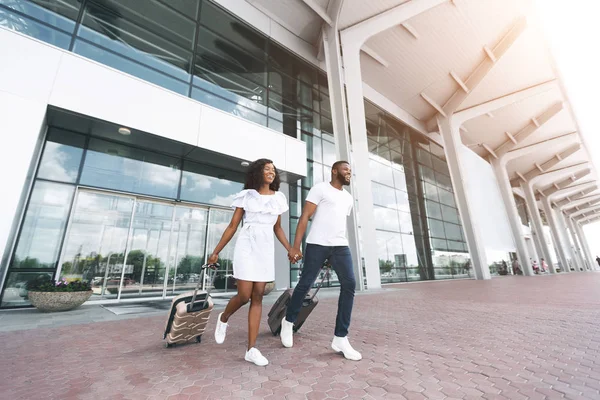 Joven pareja negra corriendo con equipaje en el edificio del aeropuerto — Foto de Stock