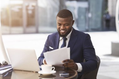 İşadamı Laptop'ta Oturarak Açık Kafede Kağıtlarla Çalışıyor