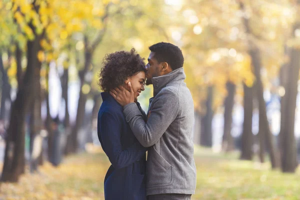 Negro joven besar su novia frente mientras caminar —  Fotos de Stock