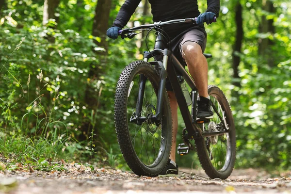 Sporty body of young cyclist riding bike down the woods — Stock Photo, Image