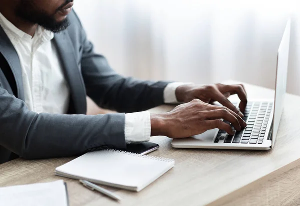 Un employé afro-américain travaillant sur un ordinateur portable dans un bureau moderne — Photo