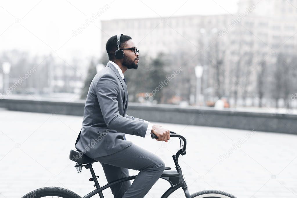 Young man with headphones riding bicycle on city street