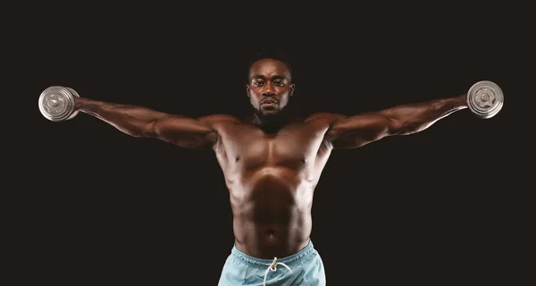 African American kulturysta podnoszenie hantlami się z prostymi ramionami — Zdjęcie stockowe