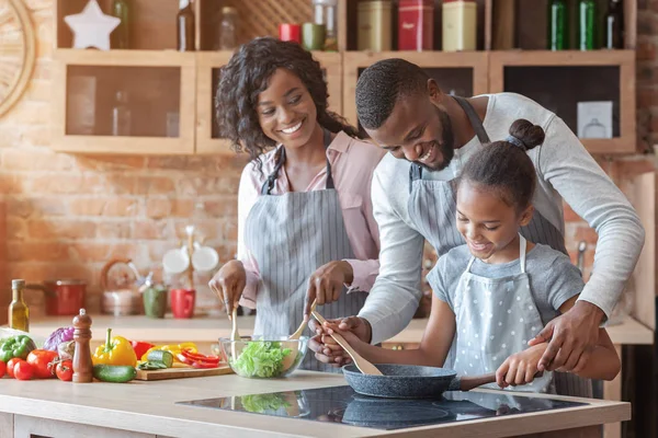 Afrikaanse ouders onderwijzen hun dochter hoe te koken — Stockfoto