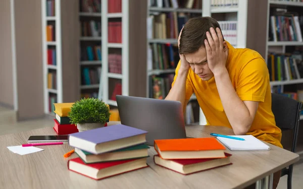 Estudante cansado sentado na frente do laptop, apertando a cabeça — Fotografia de Stock