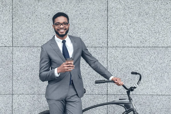 Empresário afro milenar de pé com café e sua bicicleta — Fotografia de Stock