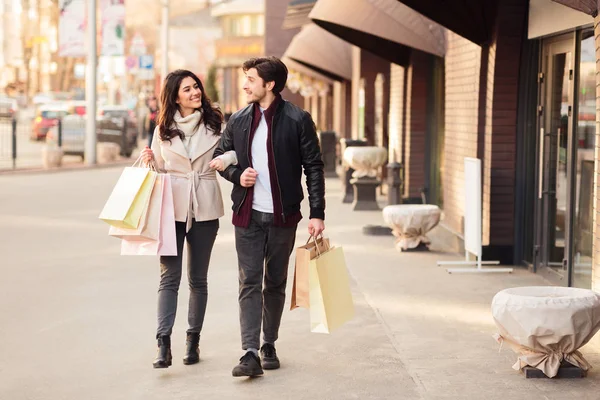 Young happy couple with shopping bags walking outdoors — Stock Photo, Image