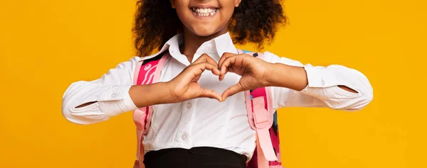无法识别的黑人女学生显示心脏形状手势在黄色背景 — 图库照片