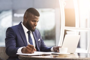 Dizüstü Bilgisayar Üzerinde Çalışan İşadamı Açık Kafede Notlar Alıyor