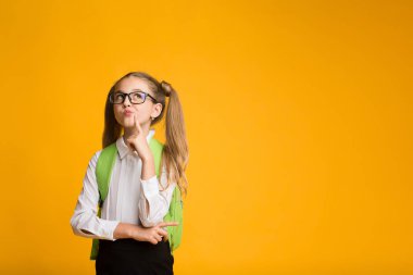 İlköğretim Öğrenci Kız Düşünme Sarı Arka Plan Üzerinde Poz.