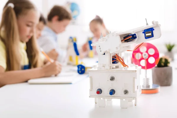Robot en el escritorio con los escolares en el fondo — Foto de Stock