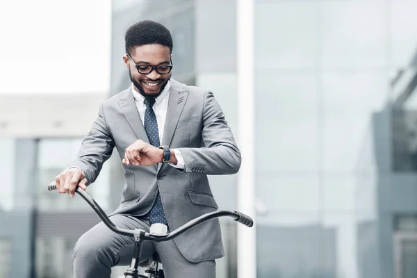 Gestor bonito verificando o tempo em seu relógio, apreciando passeio de bicicleta — Fotografia de Stock