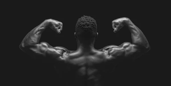 Atleta africano demostrando doble pose bíceps sobre fondo de estudio negro — Foto de Stock