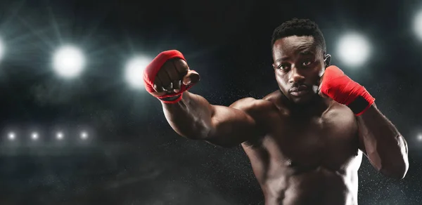 Professional black sportsman fighting on boxing arena