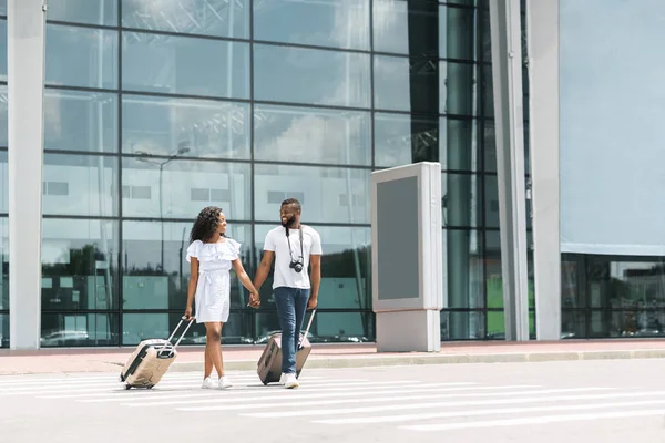 Fröhliches afrikanisches Paar genießt Urlaub, geht mit Gepäck am Flughafen spazieren — Stockfoto