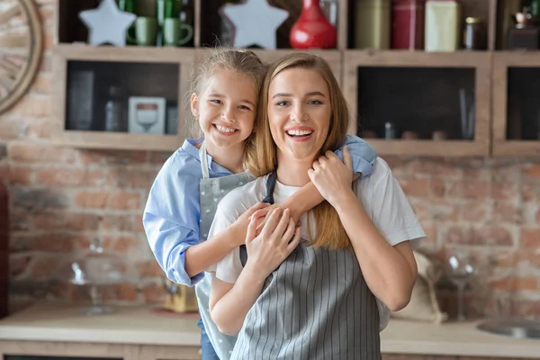 Όμορφη μαμά και κόρη αγκαλιάζοντας στην κουζίνα — Φωτογραφία Αρχείου