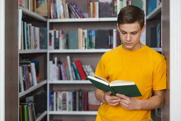 Smart manlig elev läsning bok mellan bokhyllor — Stockfoto