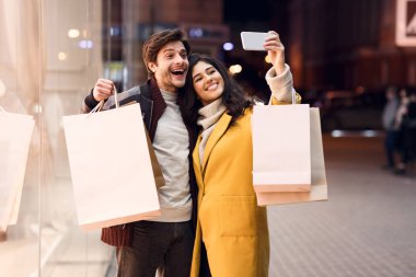 Alışveriş merkezinde alışveriş yaptıktan sonra fotoğraf çeken sevgi dolu çift