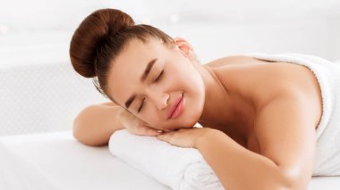 Kapalı gözlerle yatan, spa'da dinlenen kadın