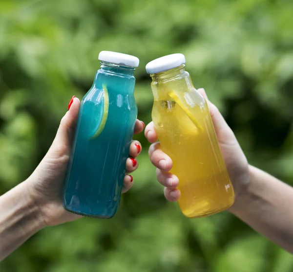 Голубой Изотоник и детоксикационный лимонад в женских руках на открытом воздухе — стоковое фото