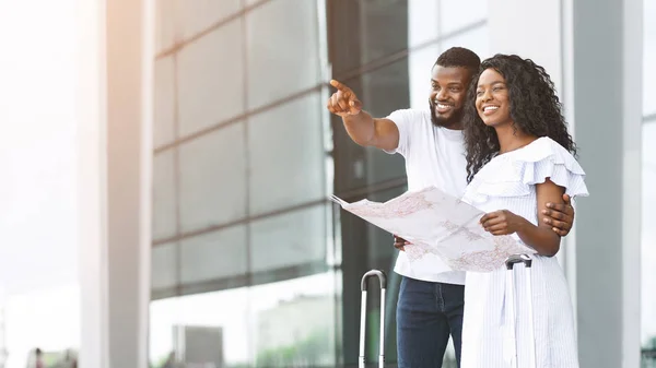 Feliz negro recién casados buscando mapa en el aeropuerto, la planificación de la luna de miel — Foto de Stock