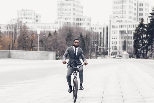 Afro homem de terno andar de bicicleta no caminho para o escritório — Fotografia de Stock