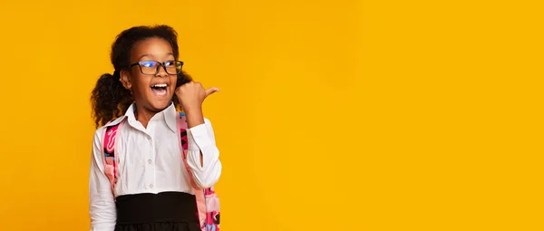 Schoolgirl Pointing Thumbs At Free Space On Yellow Background — Stock Photo, Image