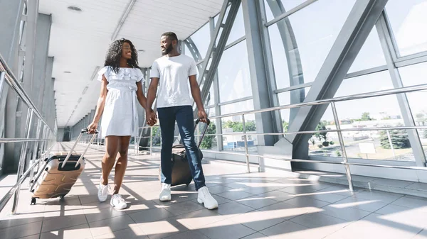 Czarna para w miłości spaceru z walizki na lotnisku — Zdjęcie stockowe