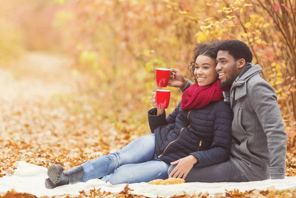 Picnic de otoño. Afro pareja bebiendo café caliente —  Fotos de Stock