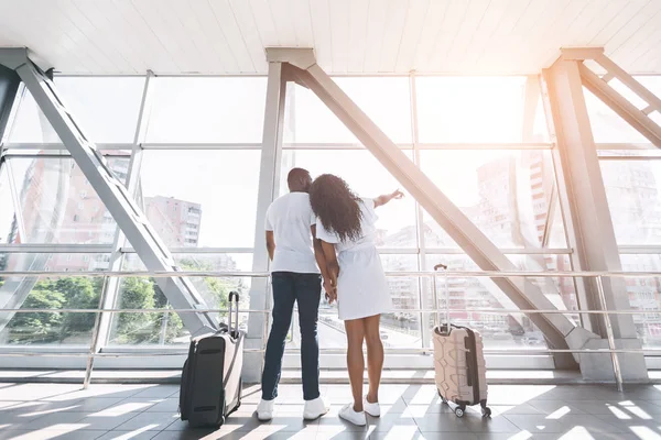 Couple noir amoureux profitant de la vue sur la ville depuis la fenêtre de l'aéroport — Photo