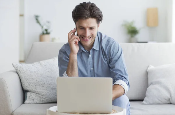 Succesvolle ondernemer praten op telefoon met behulp van laptop indoor — Stockfoto