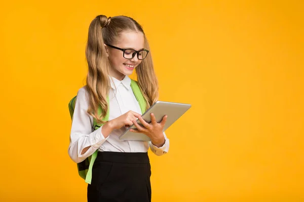 Schoolgirl Tablet Bilgisayar Tarama İnternet, Sarı Arka Plan kullanma — Stok fotoğraf