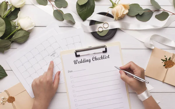 Frau schreibt Hochzeitsartikel in Checkliste für Budgetplanung — Stockfoto