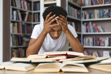 Bitkin siyah adam başını tutarak ve kütüphanede kitap okuma