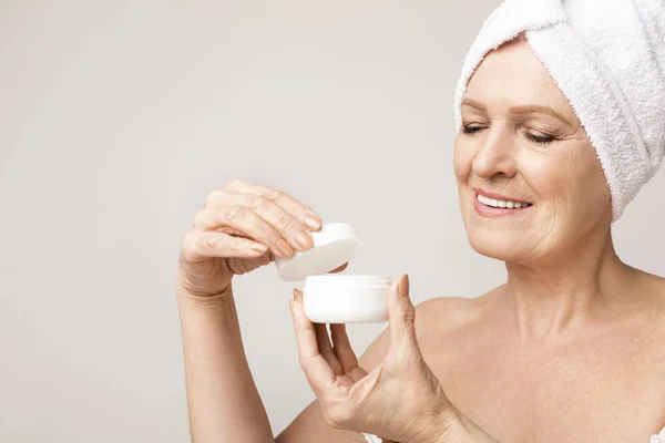 Senior lady holding open jar of face cream — Stock Photo, Image