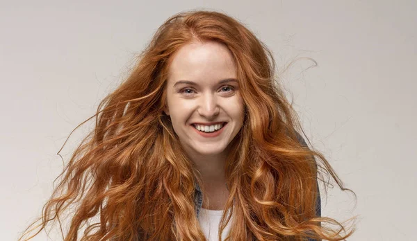 Güzel kızıl saçlı kız gülüyor, ışık arka planda kameraya bakıyor — Stok fotoğraf