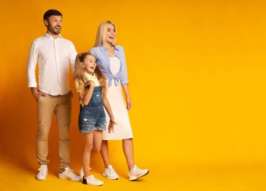 Heyecanlı aile sarı arka plan üzerinde duran boş alan bakıyor