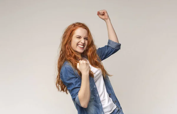 Millennial chica sacudiendo puños celebrando el éxito en fondo de estudio de luz — Foto de Stock