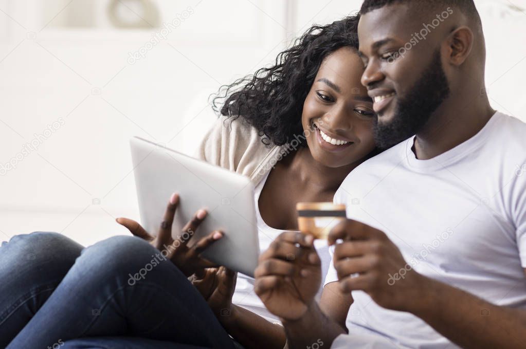 African American Couple Shopping Online Using Digital Tablet At Home
